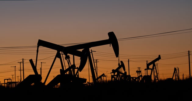 A still image of oil pump jacks working in an oilfield in Kern County, California on a Spring sunset.