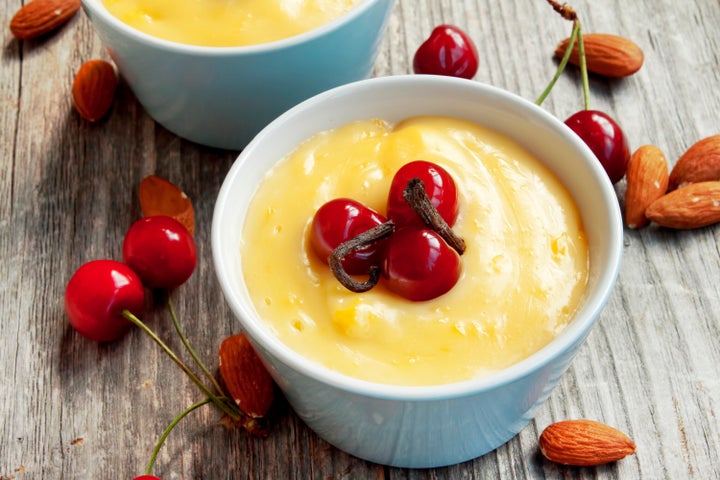 cups with vanilla pudding, ripe cherries and almonds with vanilla sticks