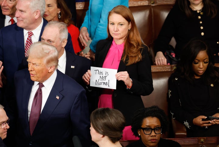 Rep. Melanie Stansbury (D-N.M.) holds a sign reading "This is not normal" as President Donald Trump arrives to address a joint session of Congress.