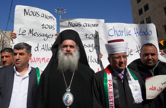 Ο Παλαιστίνιος Ελληνορθόδοξος Αρχιεπίσκοπος Atallah Hanna, στο κέντρο αριστερά, περπατά δίπλα στον Σεΐχη Hatem al-Bakri, στο κέντρο δεξιά, σε έναν δρόμο για να διαμαρτυρηθεί ενάντια σε ένα σκίτσο του Προφήτη Μωάμεθ του Ισλάμ που δημοσιεύθηκε από το γαλλικό σατιρικό περιοδικό Charlie Hebdo την περασμένη εβδομάδα, καθώς διαδηλωτές διαδηλώνουν στην πόλη της Χεβρώνας στη Δυτική Όχθη, Πέμπτη 22 Ιανουαρίου 2015. (AP Photo/Nasser Shiyoukhi)