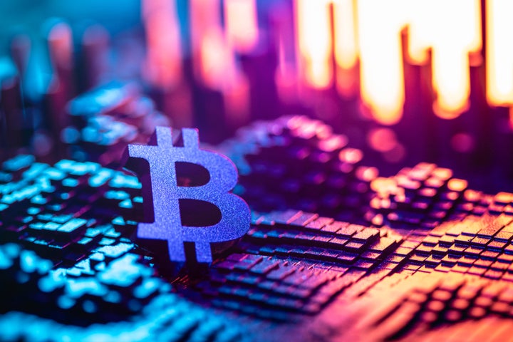 A glowing Bitcoin symbol stands prominently against a colorful background, showcasing digital and blockchain concepts.