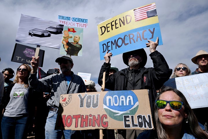 Susie House, front, and David Hill hold up signs as they join hundreds of others during a large rally and protest outside the National Oceanic and Atmospheric Administration campus Monday, March 3, 2025, in Boulder, Colorado.