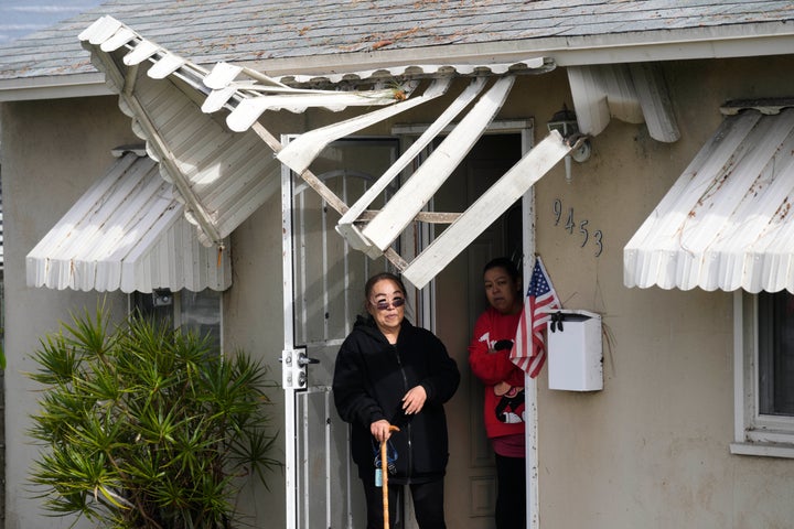 Resident Nicole Hiromoto, in black, stands under a damaged awning with Susie Gonzales, after a storm passed Thursday, March 13, 2025, in Pico Rivera, Calif.