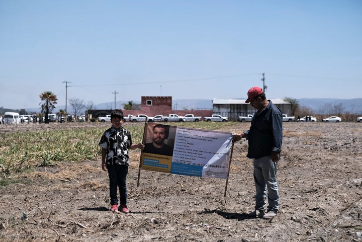 People hold a photo of a missing relative outside Izaguirre Ranch on Thursday.