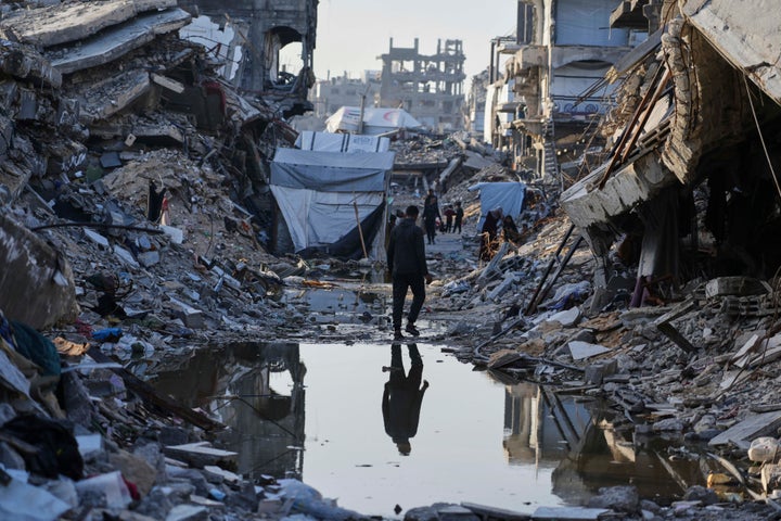 Palestinians walk amid the rubble of destroyed homes and buildings in Jabaliya, northern Gaza Strip on Friday, March 14, 2025. (AP Photo/Jehad Alshrafi)