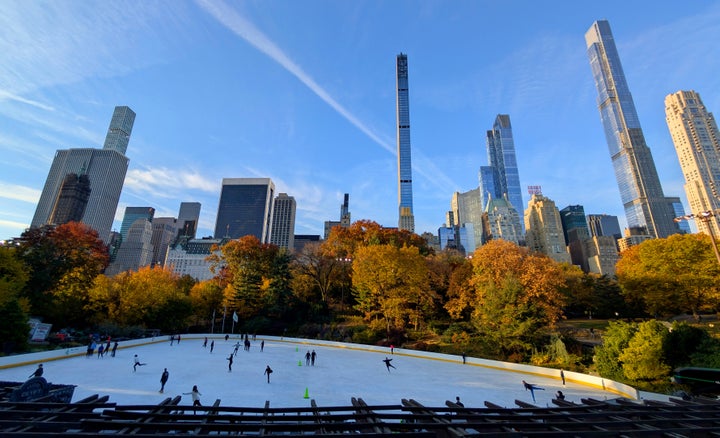 People ice skate on the Wollman Rink in front of trees turning color in Central Park as the sun rises on October 28, 2024, in New York City. (Photo by Gary Hershorn/Getty Images)