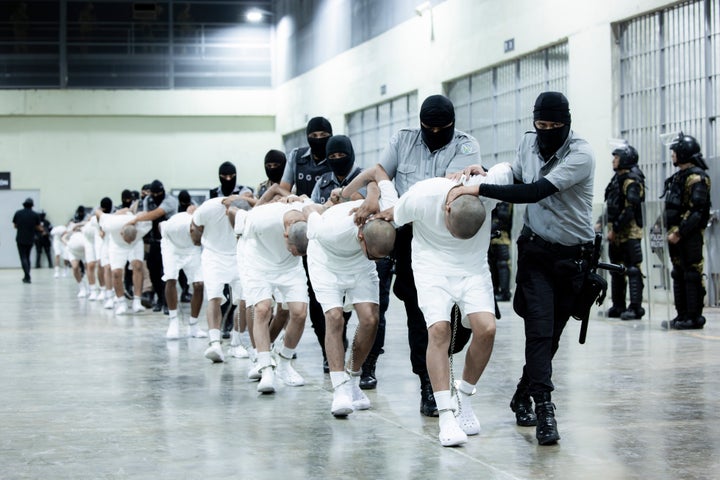 In this photo provided by El Salvador's presidential press office, prison guards transfer deportees from the U.S., alleged to be Venezuelan gang members, to the Terrorism Confinement Center in Tecoluca, El Salvador, Sunday, March 16, 2025. (El Salvador presidential press office via AP)