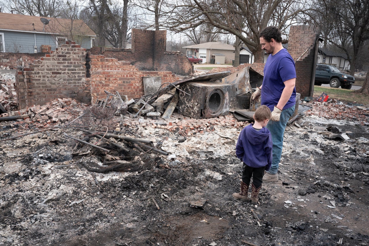 Zach Johnson and his son Owen salvage items from their home after it was destroyed by Friday's wildfires in Mannford, Oklahoma.