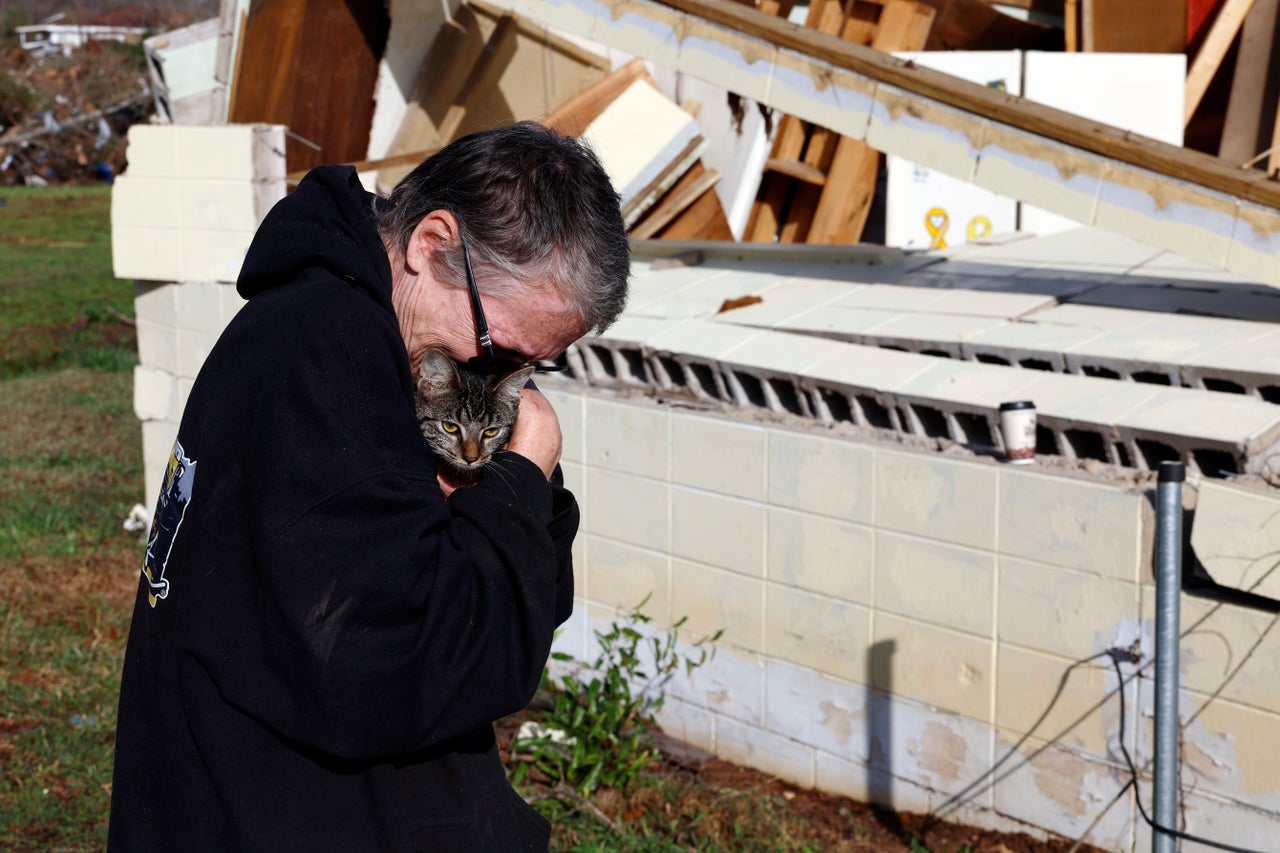 Emily Robertson reunites Sunday with one of her cats as she looks for personal belongings in the damage after a tornado passed through where two people lost their lives in Plantersville, Ala.