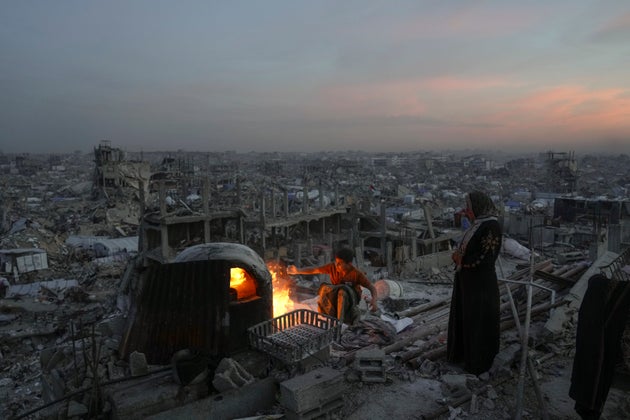 Palestinians Ali Marouf and his mother Aisha cook on fire on the roof of their destroyed house by the Israeli army's air and ground offensive in Jabaliya, Gaza Strip, on Monday, March 17, 2025. 