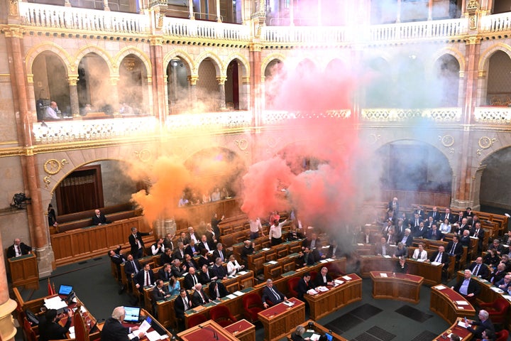Members of the centrist Momentum Movement party burn flares in protest before a vote on a bill aimed at banning the annual Pride march on March 18, 2025, during the spring session of the Hungarian Parliament. 
