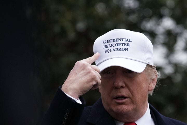 President Donald Trump points to his cap in December 2017.