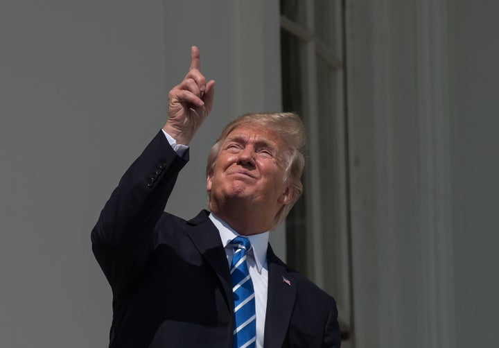 President Donald Trump looks — and points, naturally — at the solar eclipse from the balcony of the White House on Aug. 21, 2017.