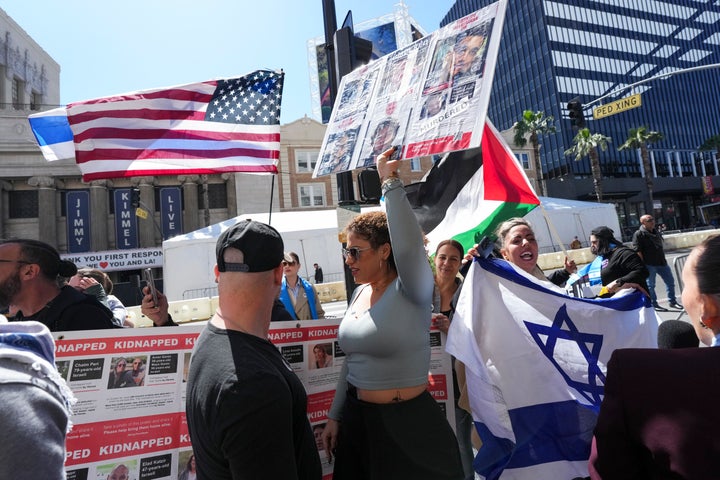 People hold signs and flags referencing the Israel-Hamas war outside of the area where Gadot was honored with a star on the Hollywood Walk of Fame on Tuesday.