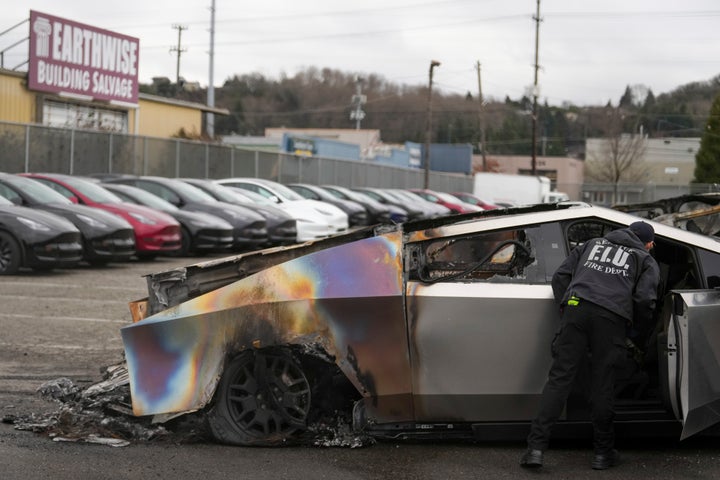 A member of the Seattle Fire Department inspects a burned Tesla Cybertruck at a Tesla lot in Seattle.