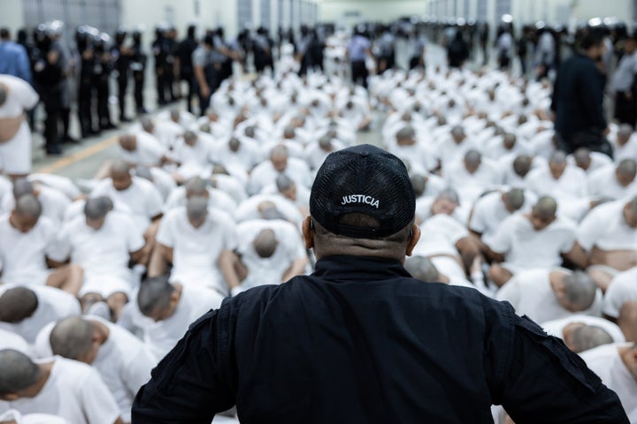 A guard watches inmates sitting on the floor at CECOT, the forced labor prison in El Salvador where detainees were rendered by the Trump administration on Saturday.