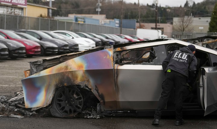A member of the Seattle Fire Department inspects a burned Tesla Cybertruck at a Tesla lot in Seattle, Monday, March 10, 2025. (AP Photo/Lindsey Wasson)