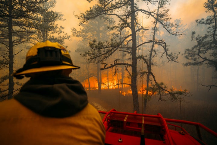 A firefighter looks on as the California Branch wildfire burns in New Jersey's Wharton State Forest, on Saturday, March 22, 2025.