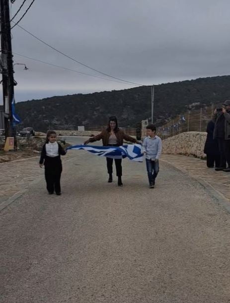 Γαύδος, 25 Μαρτίου 2025 - Η μοναδική δασκάλα στο νησί, κρατάει μαζί με τους 2 μαθητές της την ελληνική σημαία για την παρέλαση της 25ης Μαρτίου.