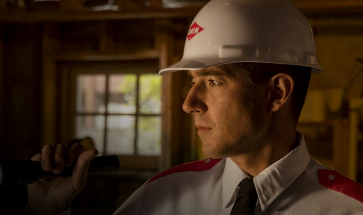 An Orkin expert with a flashlight and hard hat