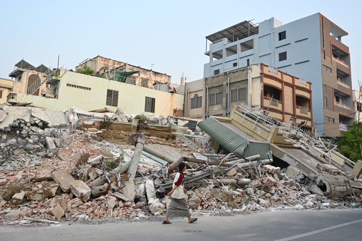 A woman walks past destroyed buildings in Mandalay on April 1, 2025, four days after a major earthquake struck central Myanmar. (Photo by STR/AFP via Getty Images)