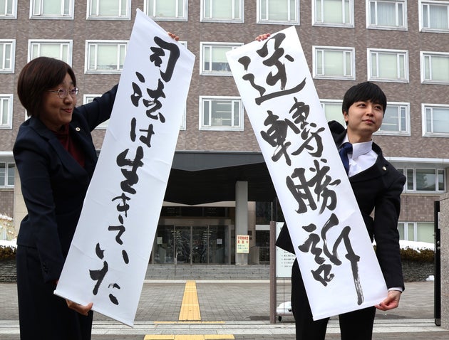 生活保護引き下げ訴訟で、札幌高裁の控訴審判決を受け「逆転勝訴」と書かれた紙を掲げる原告側弁護士ら＝3月18日、札幌市中央区