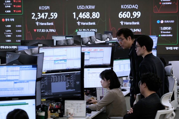 Currency traders watch monitors near a screen showing the Korea Composite Stock Price Index (KOSPI), top left, and the foreign exchange rate between U.S. dollar and South Korean won, top center, at the foreign exchange dealing room of the KEB Hana Bank headquarters in Seoul, South Korea, Monday, April 7, 2025. (AP Photo/Ahn Young-joon)