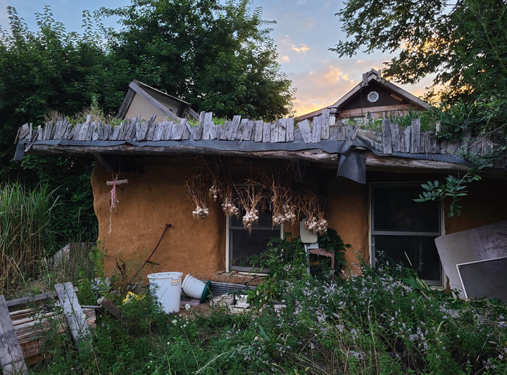 A house with garlic drying along its eaves at Dancing Rabbit Ecovillage in Rutledge, Missouri (July, 2023).