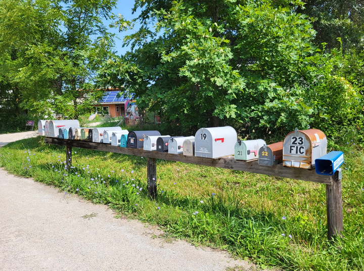 A row of mailboxes for the residents at Dancing Rabbit Ecovillage in Rutledge, Missouri (July 2023). "They’re lined up outside the community, since cars are not allowed within it," the author writes.