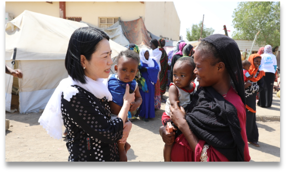 スーダンの国内避難民キャンプで女性と話をする新垣尚子さん（左）＝2024年4月、UNFPA提供