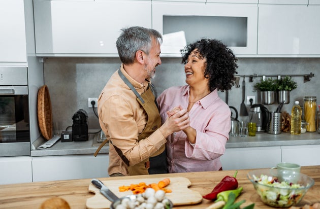 Cheerful mature couple having fun while dancing during food preparation in the kitchen