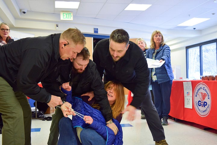 Employees of a security firm, LEAR Asset Management, drag Post Falls resident Teresa Borrenpohl out of a town hall meeting on Saturday, Feb. 22, 2025, in Post Falls, Idaho.