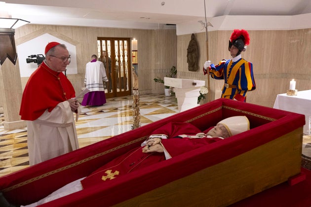 Vatican Secretary of State Cardinal Pietro Parolin, left, prays in front of the body of Pope Francis laid out in state inside his private chapel at the Vatican, Monday, April 21, 2025.