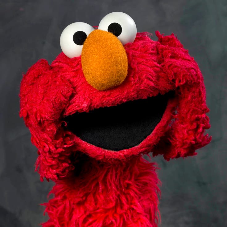 This file photo shows "Sesame Street" muppet Elmo posing for a portrait in 2011 with the assistance of puppeteer Kevin Clash. Elmo and his friends are facing an uncertain future amid changes to its contracts and Trump administration cuts.