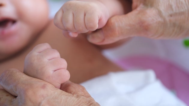 Τα χέρια νεογέννητου μωρούμ μέσα σε αυτά της γιαγιάς του