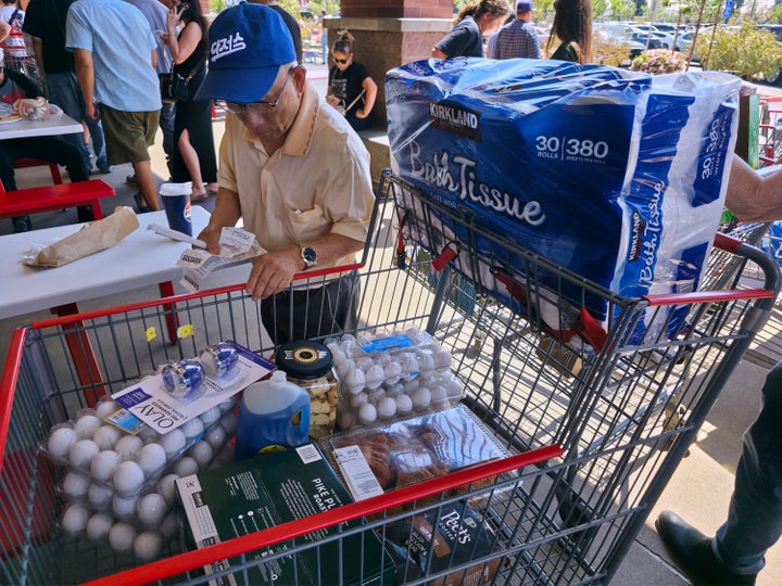 A customer checks his shopping receipts while waiting in line at the food court at Costco Wholesale store in Glendale, Calif., on Thursday, April 10, 2025. (AP Photo/Damian Dovarganes, File)