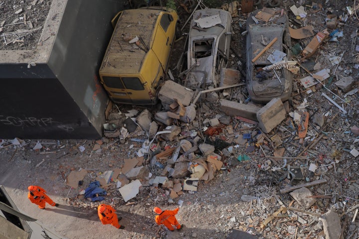 Communal workers stand next to destroyed cars in the courtyard of a residential building following a drone attack in Odesa on May 1, 2025, amid the Russian invasion of Ukraine.