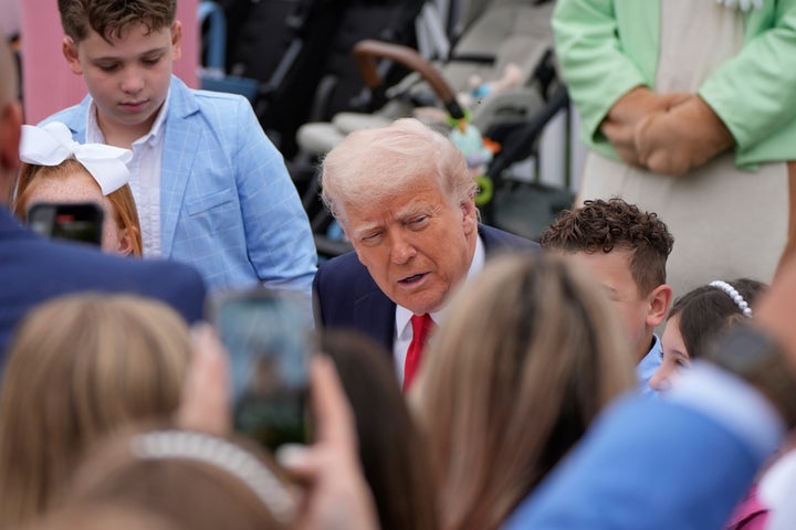 President Donald Trump sits with children, who he says might have to go with "two dolls instead of 30" under his tariff plan.