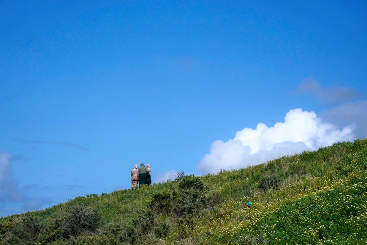 Women stand atop a hill as they watch a protest outside Tangier Med Port, Sunday, April 20, 2025.