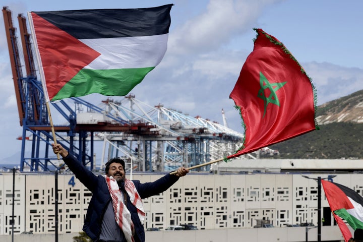 A man waves Palestinian and Moroccan flags during a protest outside the Tangier-Med Port against the planned docking of a ship suspected to be carrying fighter jet parts to Israel, on April 20, 2025.