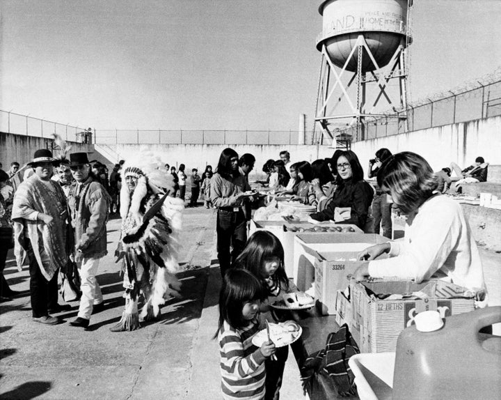 Native Americans occupying the former federal prison on Alcatraz Island, off the coast of San Francisco, celebrate their Thanksgiving Day feast buffet-style in the exercise yard of the prison, Nov. 28, 1969. (AP Photo/Robert W. Klein)