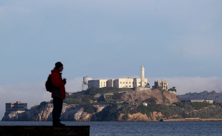 A man stands on a pier with Alcatraz Island at rear in San Francisco, Saturday, Dec. 22, 2018. (AP Photo/Jeff Chiu)