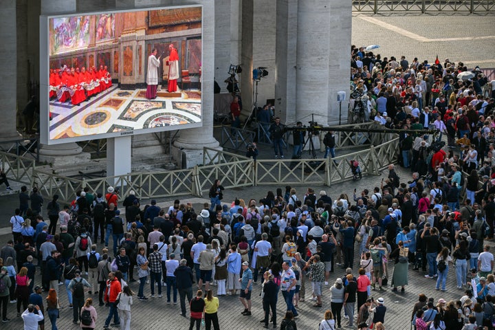Visitors watch the cardinal's procession to the Sistine Chapel displayed on a screen, ahead of the conclave, on St Peter's Square in the Vatican, on May 7, 2025.