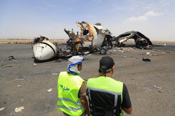 Airport employees stand next to a destroyed plane at the Sanaa International Airport on May 7, 2025, a day after Israel's military warplanes struck Yemen's rebel-held capital. Israel's attack on the airport came in response to a Houthi missile striking the grounds of Ben-Gurion International Airport near Tel Aviv.