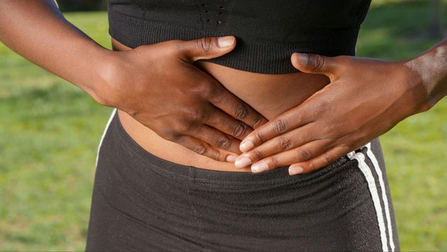 Black woman holding hands over abdomen.
