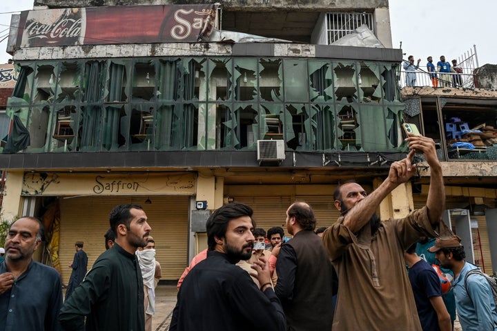 People gather in front of the shattered glasses of a restaurant outside the Rawalpindi cricket stadium after an alleged drone was shot down in Rawalpindi on May 8, 2025. India and Pakistan accused each other on May 8 of carrying out waves of drone attacks, as deadly confrontations between the nuclear-armed foes drew global calls for calm. Pakistan's army said it shot down 25 Indian drones, while New Delhi accused Islamabad of launching overnight raids with "drones and missiles", and claimed it destroyed an air defence system in Lahore. (Photo by Aamir QURESHI / AFP) (Photo by AAMIR QURESHI/AFP via Getty Images) 
