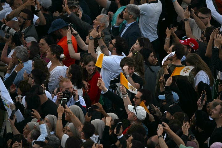 People react and wave Vatican flags as white smoke signals cardinals elected a new pope during their conclave in the Vatican on May 8, 2025.