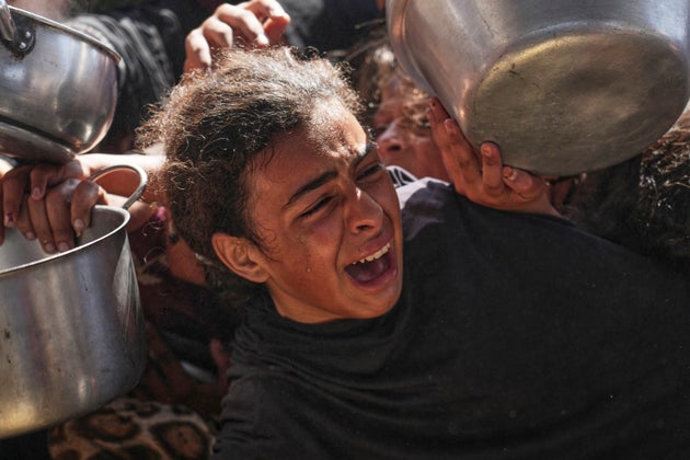 A Palestinian girl struggles to obtain donated food at a community kitchen in Khan Younis, in the southern Gaza Strip.