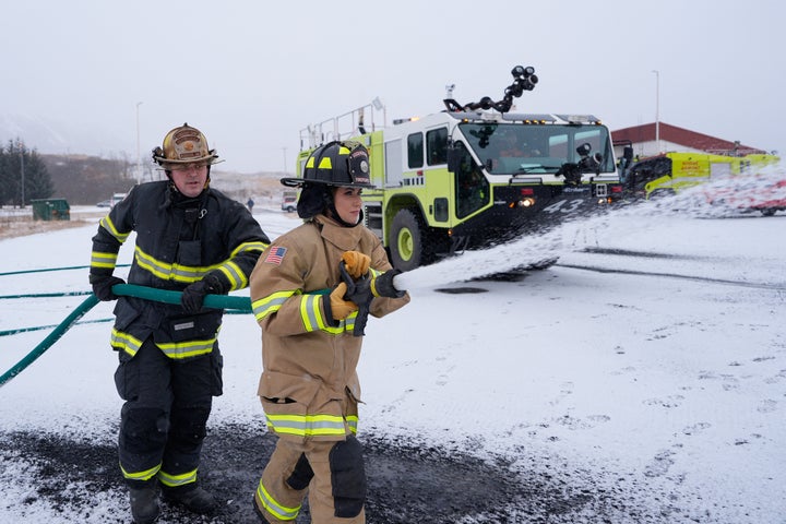 Homeland Security Secretary Kristi Noem (R), participates in a firefighting drill with a training helicopter during a tour of U.S. Coast Guard Air Station Kodiak on March 17.