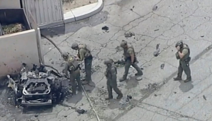 Law enforcement investigate a charred vehicle after the explosion.